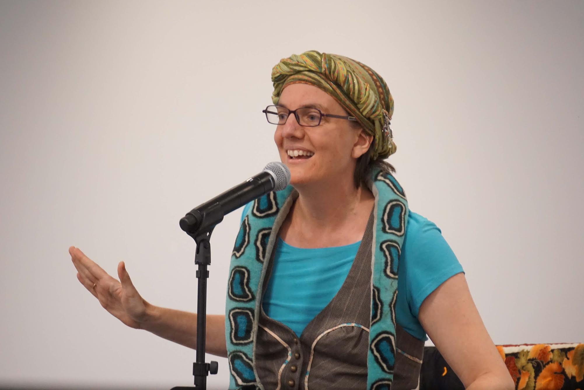 Andrea telling a story to a crowd of adults with plush snake prop